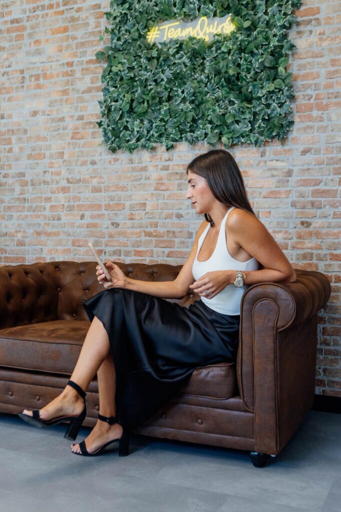 Paula Quiros, asesora inmobiliaria, sentada en un entorno profesional.